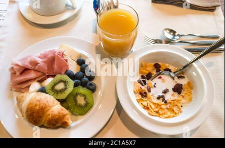 Typically Italian breakfast with cured ham, fresh cheese balls, juice and cereals Stock Photo