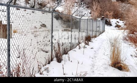 Panorama Chain link fence with barbed wires on snow covered hill slope viewed in winter Stock Photo