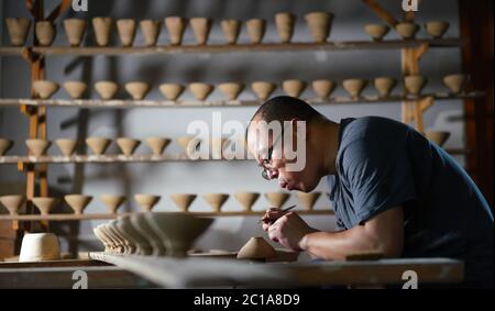 (200615) -- NANCHANG, June 15, 2020 (Xinhua) -- Craftsman Wu Yingshan makes a leaf cup at his studio in Ji'an County, east China's Jiangxi Province, June 10, 2020.  There are no two identical leaf cups, just as there are no two identical leaves in the world. The making of a leaf cup, a traditional craft endemic in today's Ji'an County, is special -- the artisan has to integrate a leaf into the porcelain ware being worked on.    Wu Yingshan, an inheritor of the leaf cup making techniques, started to study on porcelain in 2003. With the development of bulk production, the traditional ways to mak Stock Photo