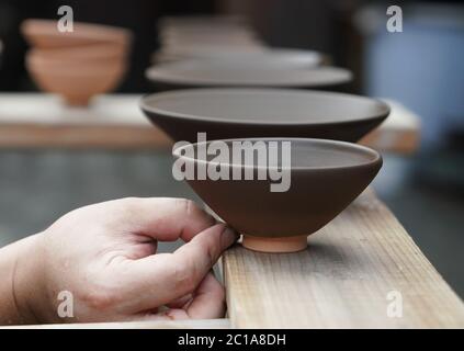 (200615) -- NANCHANG, June 15, 2020 (Xinhua) -- Craftsman Wu Yingshan dries cups at his studio in Ji'an County, east China's Jiangxi Province, June 9, 2020.  There are no two identical leaf cups, just as there are no two identical leaves in the world. The making of a leaf cup, a traditional craft endemic in today's Ji'an County, is special -- the artisan has to integrate a leaf into the porcelain ware being worked on.    Wu Yingshan, an inheritor of the leaf cup making techniques, started to study on porcelain in 2003. With the development of bulk production, the traditional ways to make leaf Stock Photo