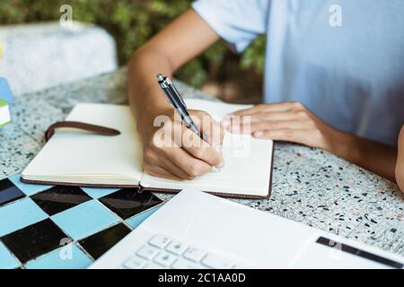 close up of woman's hands hold pen and writing in notepad Stock Photo