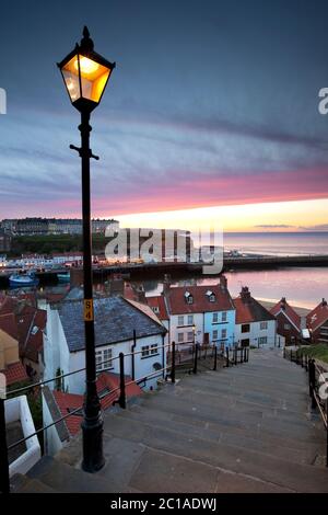 Looking down steep steps at dusk over the Old Town and West Cliff, Whitby, North Yorkshire, England, United Kingdom, Europe