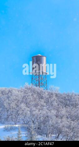 Vertical crop Snow covered Wasarch Mountains in winter with water tank tower against blue sky Stock Photo