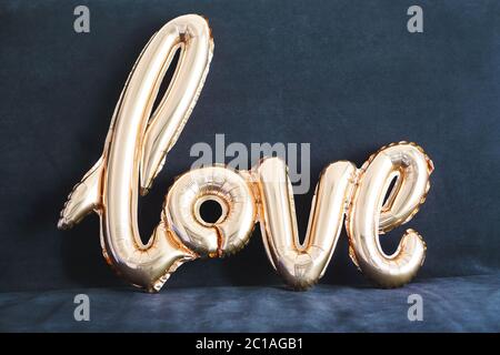 Shaped golden balloon of word Love on dark background Stock Photo