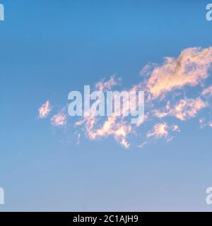 Square Wispy white clouds tinged pink at sunset Stock Photo
