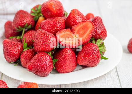 Large ripe strawberries are collected from the garden. On a white wooden background. Homemade winter fruit blanks. Selective focus. Copy space Stock Photo