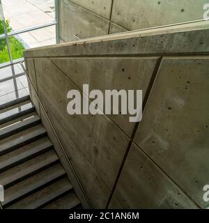 Square Commercial building interior with staircase and handrails between concrete walls Stock Photo