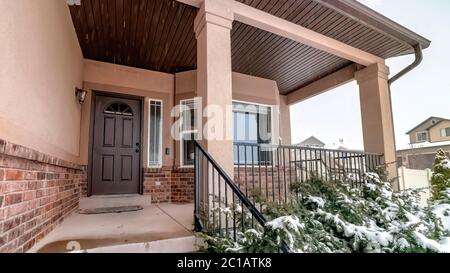 Panorama Home with bay window sidelight and glass paned wooden door against cloudy sky Stock Photo