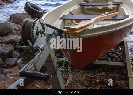 A red rowing boat (oar boat) on a slipway with a winch on lake shore in Finland Stock Photo
