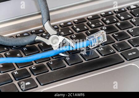 Pliers cutting internet cable on computer keyboard Stock Photo