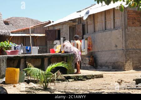Girls washing clothes with buckets and drying them on washing line, Ampangorinana Village, Nosy Komba Island, Madagascar. Stock Photo