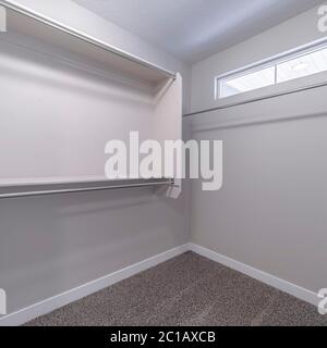 Square frame Empty walk in closet interior with small window carpet floor and white wall Stock Photo