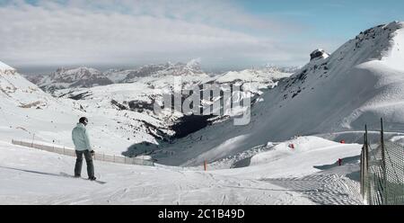 A girl on a snowboard pulls off the mountain towards the villages Corvara and Colfosco. Dolomite Alps (Sella Ronda). Italy. Stock Photo