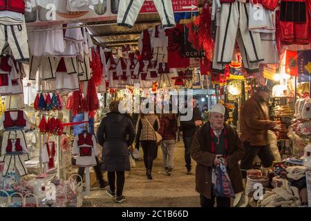 GNJILANE, GJILAN - KOSOVO - JANUARY 2, 2016: Stall on the Gjilan Bazar market with albanian flags and other national traditional cosutmes and clothimg Stock Photo