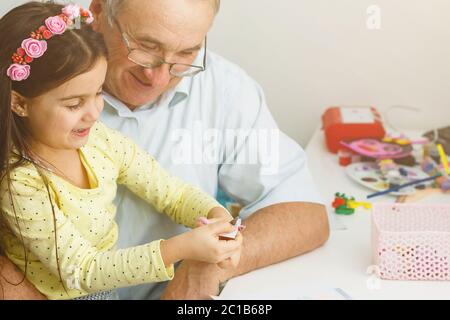 Caring grandfather doing home assignment together with granddaughter Stock Photo