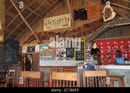 Interior of local pub with people at the bar, Ampangorinana Village, Nosy Komba Island, Madagascar. Stock Photo