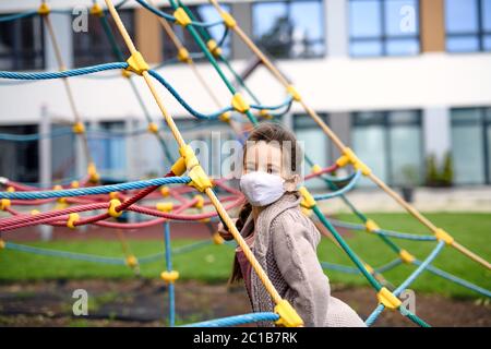 Portrait of happy child with face mask on playground after covid-19 lockdown. Stock Photo