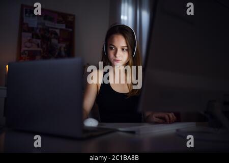 Bored young girl with computer sitting indoors, online chatting concept. Stock Photo