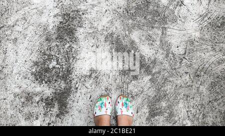 Cracked concrete floor, natural texture. Light table. Feet are on the floor. Abstraction. Stock Photo