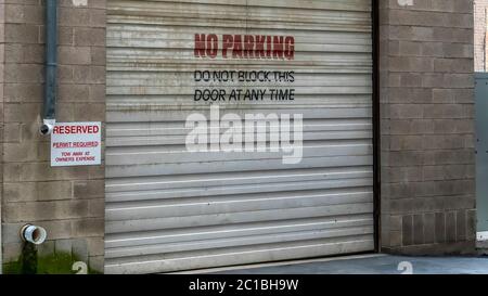 Panorama Corrugated metal garage door of an old brick building with No Parking sign Stock Photo