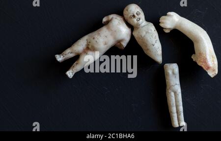 Creepy retro broken doll face and body parts isolated on grunge black background Stock Photo