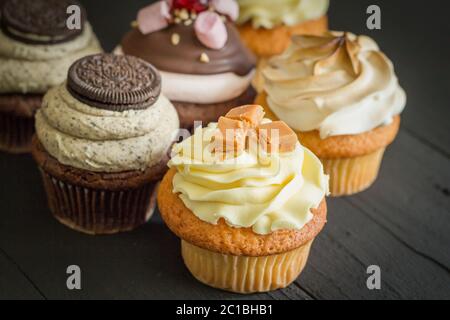 Decorated cup cakes on black table - selective focus Stock Photo
