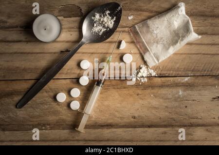 Drugs, powder, spoon, and tablets on rustic wooden background. Drug addiction concept background wit Stock Photo