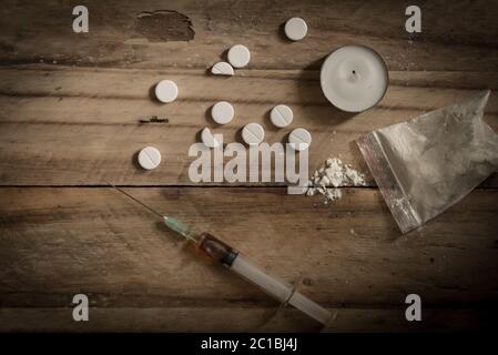 Drugs, powder, syringe and tablets on rustic wooden floor background. Drug addiction concept backgro Stock Photo