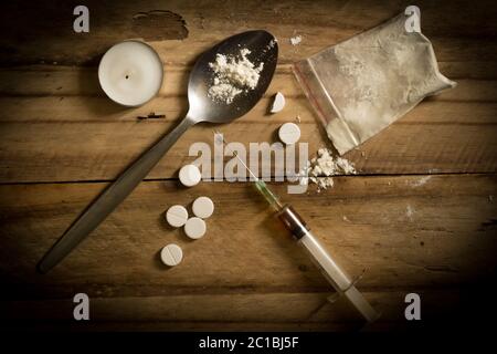 Drug addiction background with drugs, needle and spoon on grungy dirty wooden background Stock Photo