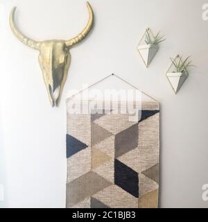 Square Woven tapestry metal bull head and plant hanger decorations against white wall Stock Photo