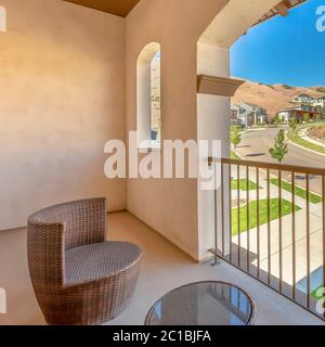 Square crop Balcony of home with wicker chair round glass table and arched window Stock Photo