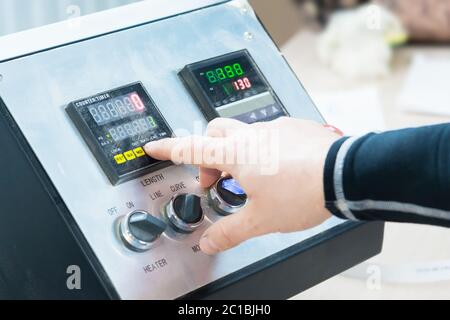 a close-up of the operator the man presses the button on the control panel with the control devices on the furniture production. Stock Photo