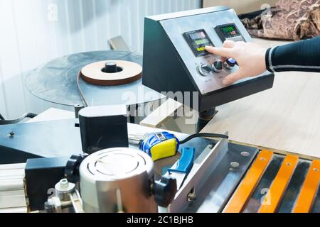a close-up of the operator the man presses the button on the control panel with the control devices on the furniture production. Stock Photo