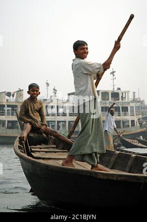 Sadarghat in Dhaka, Bangladesh. Two boys on a small boat at Sadarghat in Dhaka. Many local people in Bangladesh cross the river in this way. Stock Photo