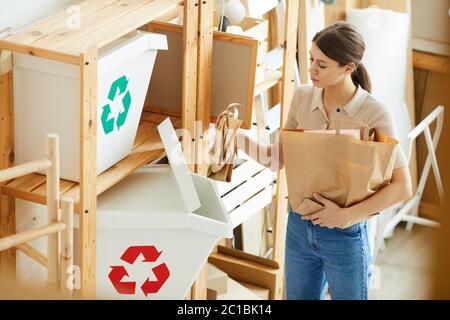 Young woman sorting paper bags into the plastic containers while standing in the warehouse Stock Photo