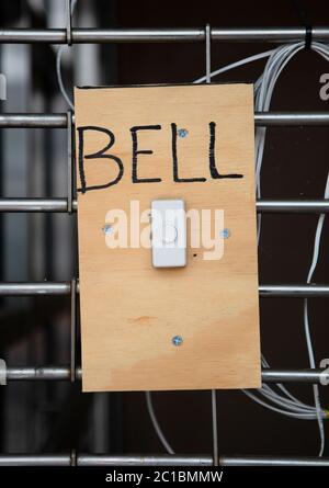 A white door bell on a piece of wood with screws with the word Bell Stock Photo