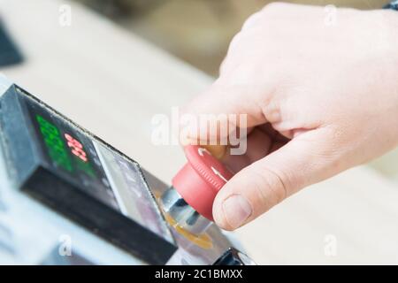 Close-up of a man's hand on a red button on the control panel. Emergency stop or start of equipment and production Stock Photo