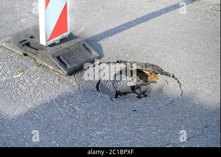 Pothole on asphalt street with detour alert traffic sign Stock Photo
