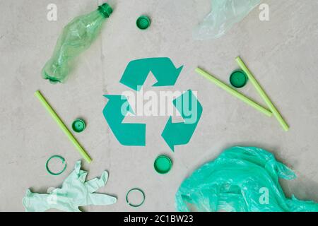 Close-up of green recycling symbol with plastic bottles and bags isolated on grey background Stock Photo