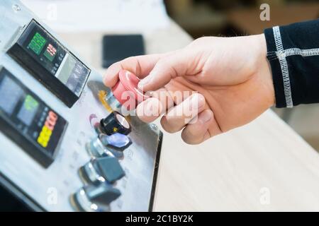 Close-up of a man's hand on a red button on the control panel. Emergency stop or start of equipment and production Stock Photo