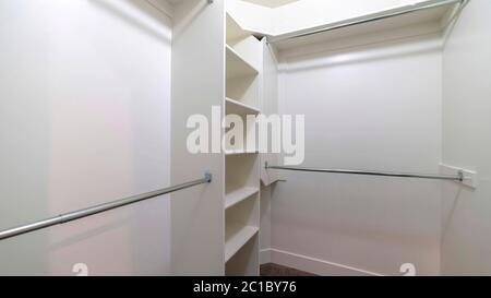 Hanging metal rods and storage shelves inside empty walk in closet of a ...
