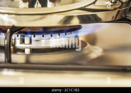 Focus of blue flame gas on a cooker boiling pot in kitchen gas stove Stock Photo