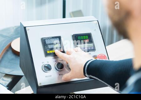a close-up of the operator the man presses the button on the control panel with the control devices on the furniture production. Stock Photo