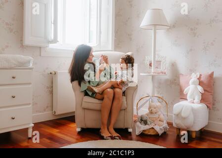 Pregnant young woman plays with her girl sitting in the room Stock Photo