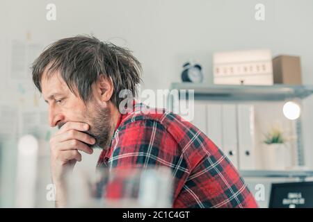 Troubled freelancer thinking in home office interior, selective focus Stock Photo