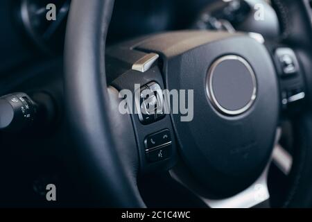 close up Modern black steering wheel with multifunction buttons Integrated stereo controls pushes the for quick control technology in the car. Stock Photo
