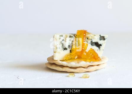 Roquefort cheese on cracker topped with orange marmalade isolated on white background Stock Photo