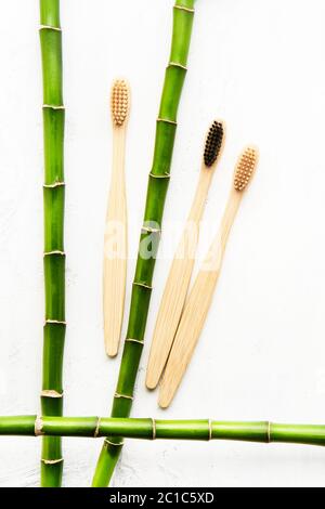 Flat lay composition with eco-friendly bamboo toothbrushes and bamboo branch on white background. Zero waste concept. Top view, copy space Stock Photo