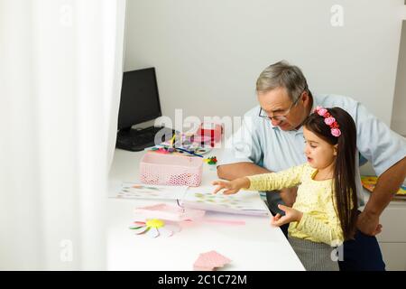 Caring grandfather doing home assignment together with granddaughter Stock Photo