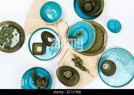 Simple rustic handmade blue crockery against white wooden wall: dish, stack of bowls. Stock Photo